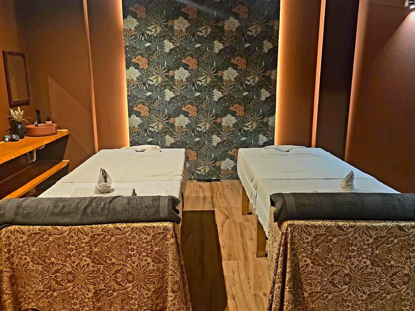 La sala de pareja: dos camillas iguales, una junto a otra, con el papel pintado botánico detrás.